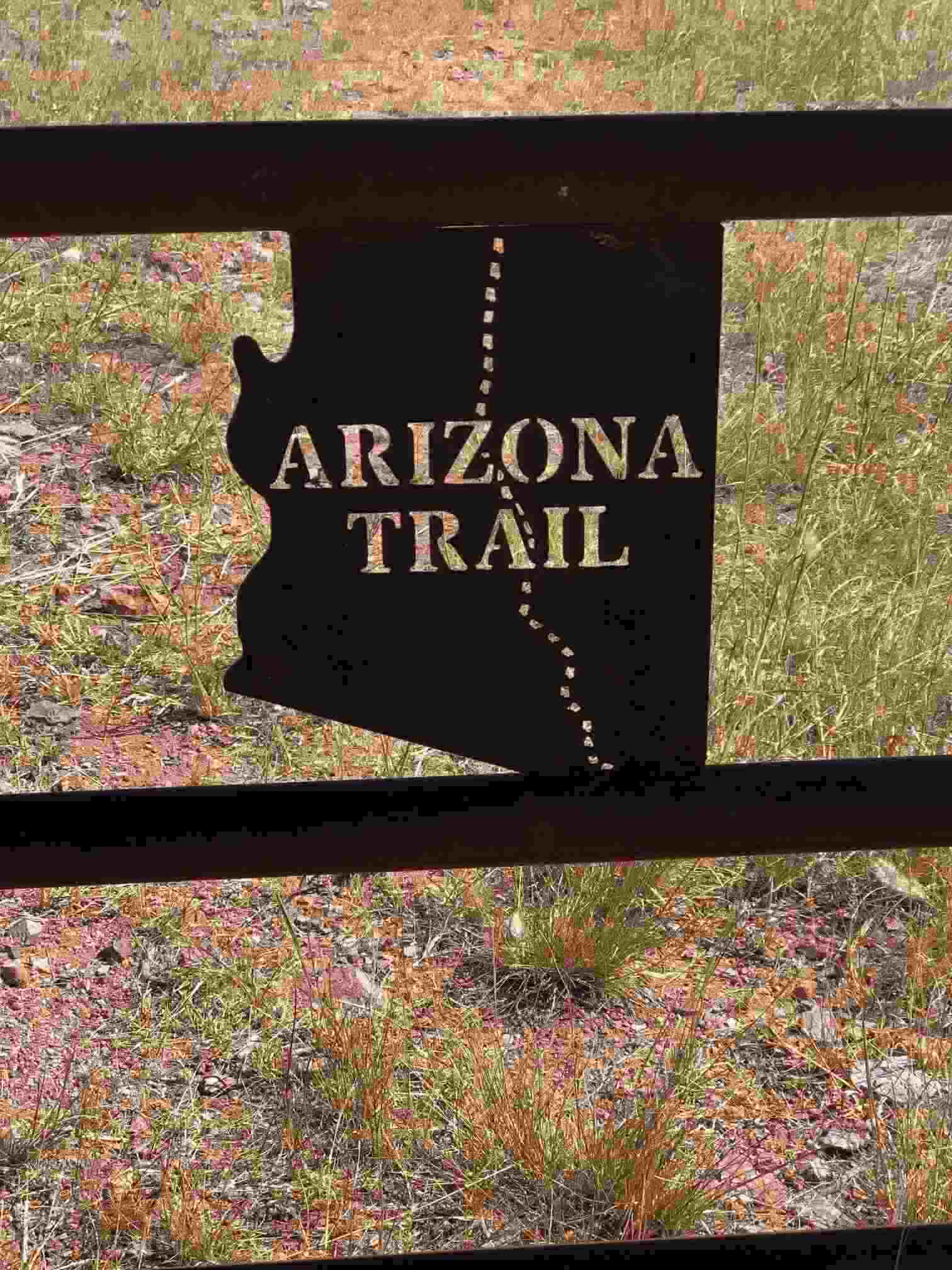 A rusty steel Arizona Trail sign marking the route, featured in the Arizona Trail Guide for bikepackers.