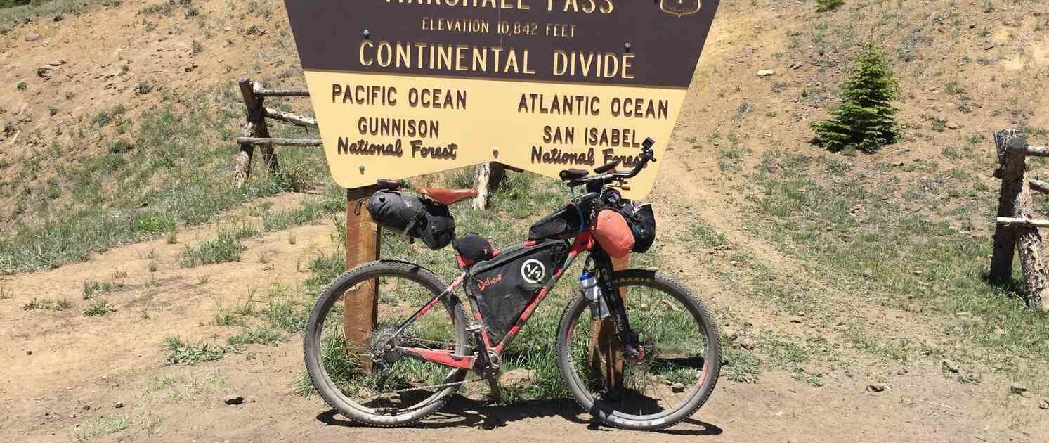 Bikepacking bike next to the Marshall Pass sign on the Tour Divide, a high-altitude crossing where altitude sickness can affect riders.