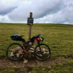 Bikepacking bike next to the Coney Summit sign, the highest point on the Colorado Trail Race (CTR), where altitude sickness can be a challenge.