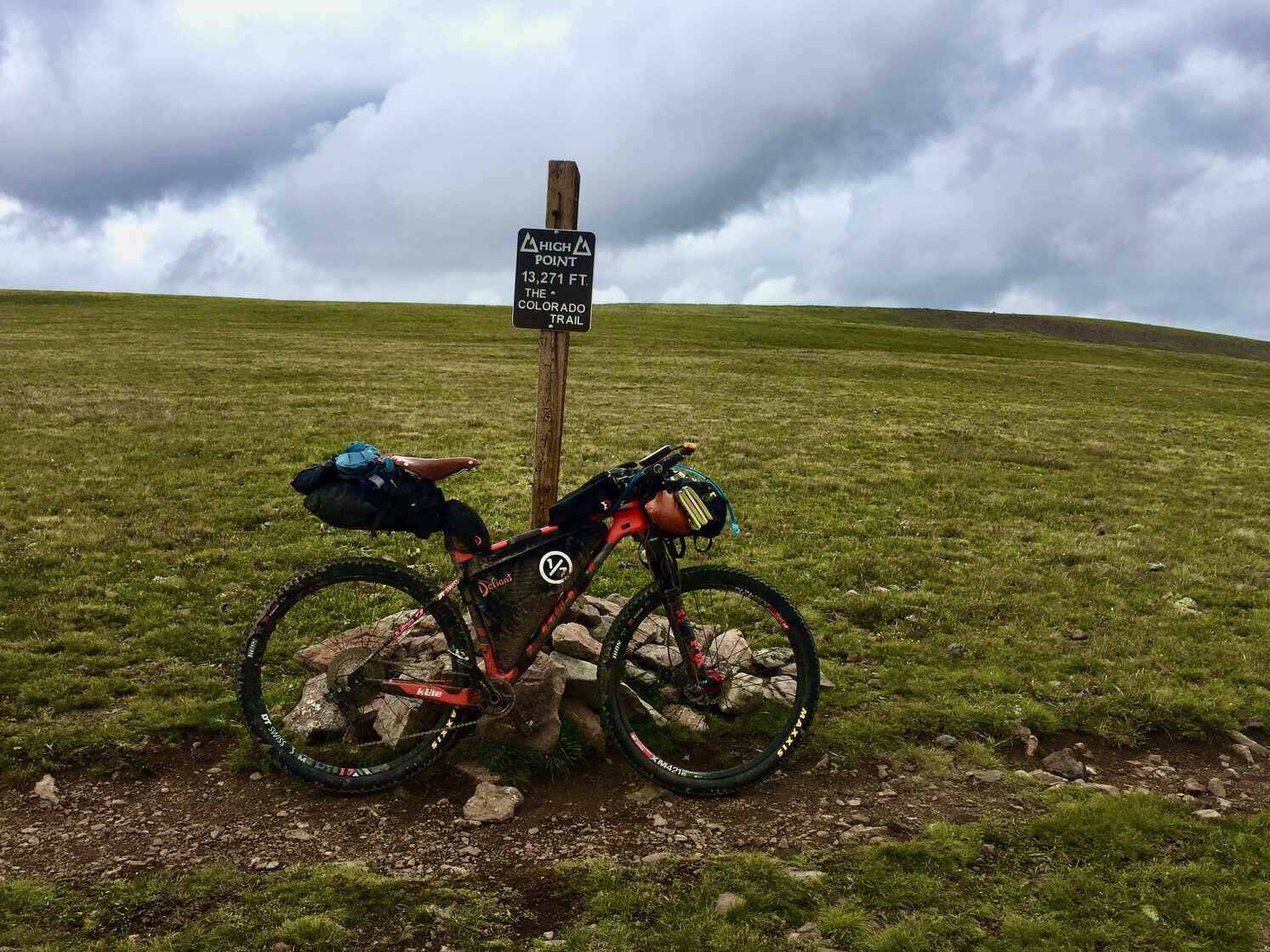 Bikepacking bike next to the Coney Summit sign, the highest point on the Colorado Trail Race (CTR), where altitude sickness can be a challenge.