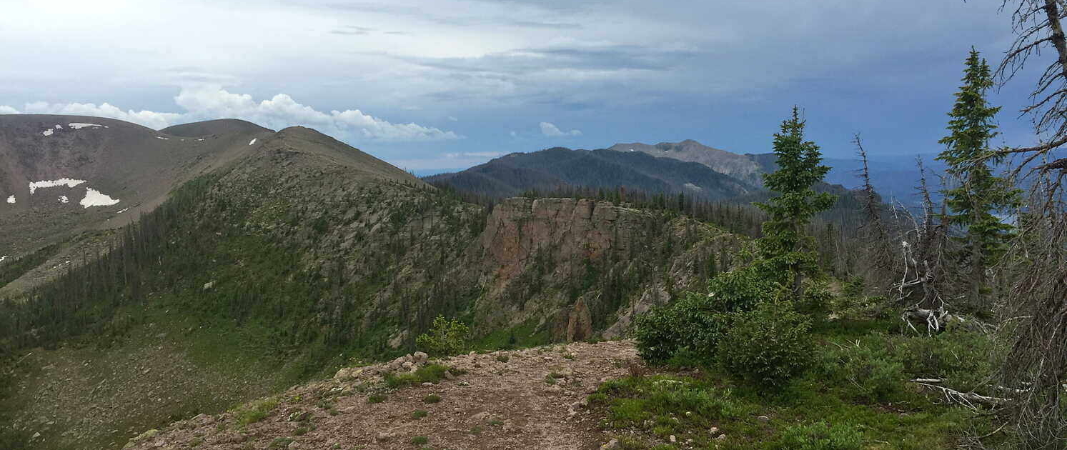 Dark storm clouds roll over the rugged peaks of the southern San Juan Mountains, highlighting the need for lightning safety for bikepackers & hikers.